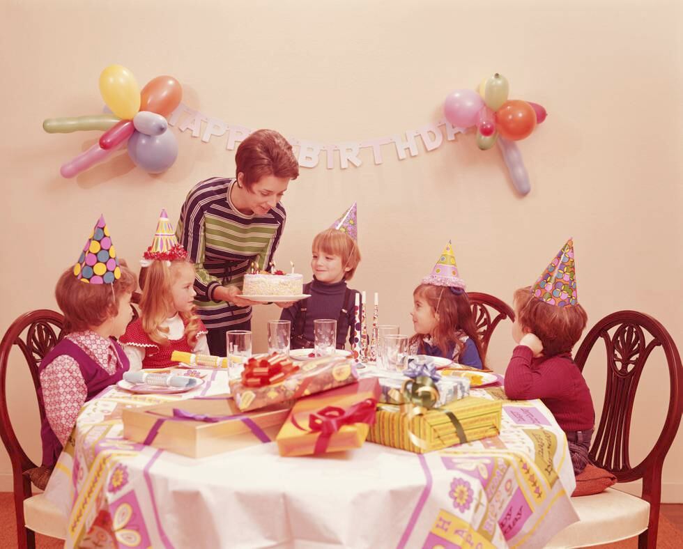 UNITED STATES - CIRCA 1970s:  Five children at birthday party, mother serving birthday cake. (Photo by H. Armstrong Roberts/Retrofile/Getty Images)