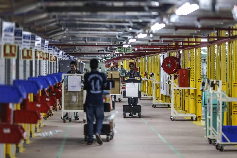 Employees push carts through Amazon.com Inc.'s fulfillment center in Hyderabad, India on Thursday, Sept. 7, 2017. Amazon opened its largest Indian fulfillment center in Hyderabad. The center spans 400,000 square feet with 2.1m cubic feet of storage capacity the company said in a statement. Photographer: Dhiraj Singh/Bloomberg via Getty Images